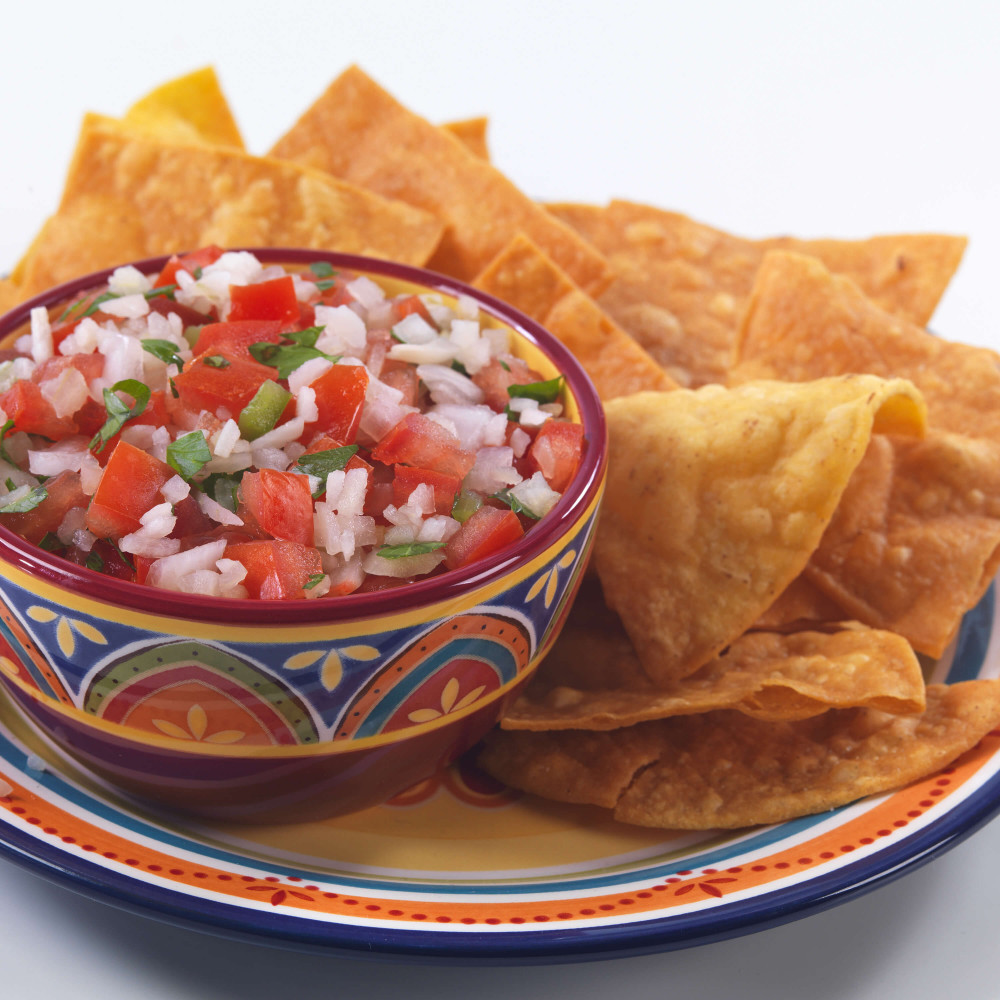 A Augason Farms Freeze-Dried Vegetable Variety Pail - 109 Servings - (SHIPS IN 1-2 WEEKS) of salsa and tortilla chips on a plate.