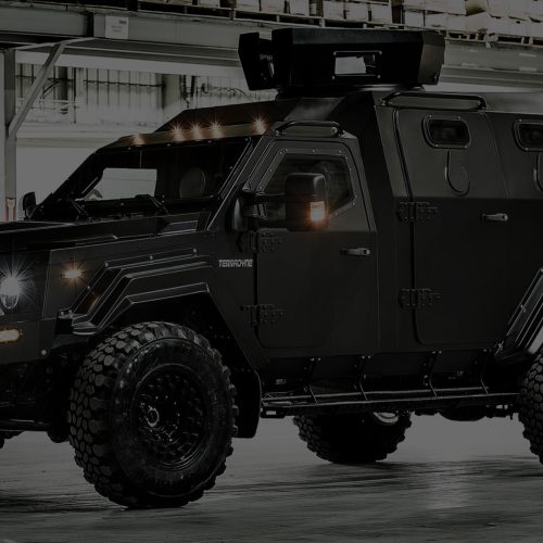 A black armored vehicle is parked in a warehouse.