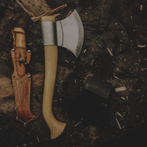 Two axes and a knife on top of a tree stump.