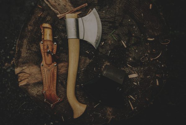 Two axes and a knife on top of a tree stump.
