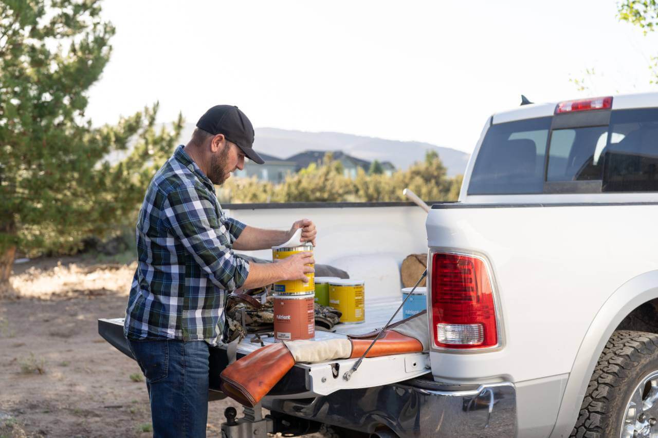 A man is putting the Nutrient Survival Homestyle Scramble #10 Can 10 Servings - (SHIPS IN 2-4 WEEKS) in the back of a truck.