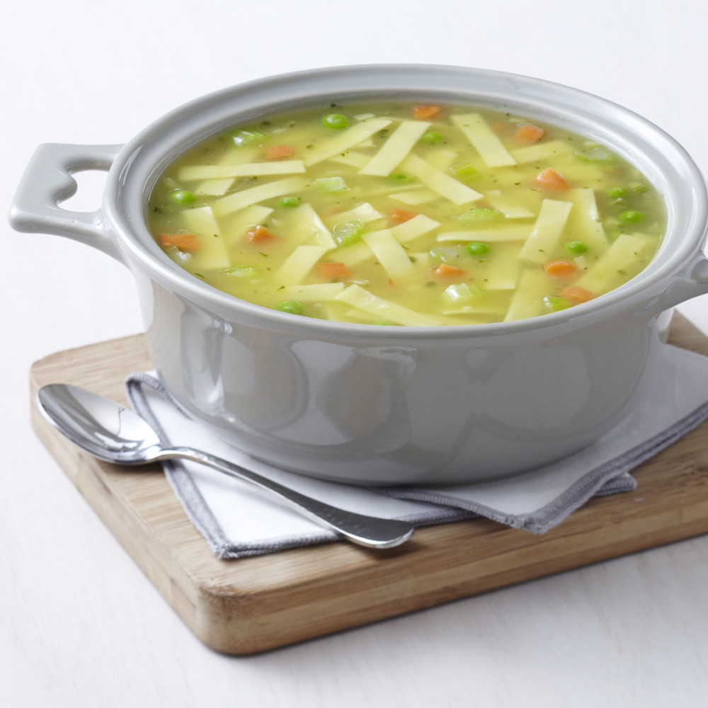 A bowl of *Augason Farms Chicken Noodle Soup Super #10 Can 20 Servings - (SHIPS IN 1-2 WEEKS) on a wooden cutting board.