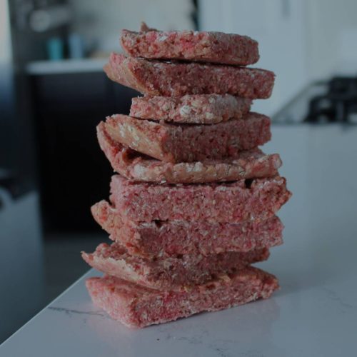 A stack of beef patties on a counter top.