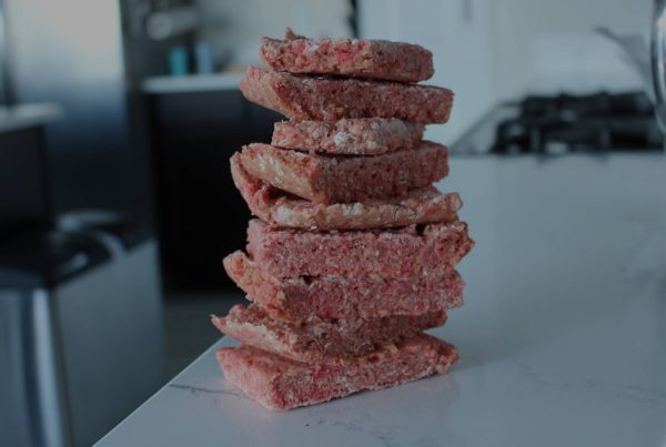 A stack of beef patties on a counter top.