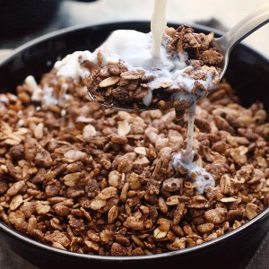 A bowl of Nutrient Survival CHOCOLATE GRAIN CRUNCH SINGLES - (SHIPS IN 2-4 WEEKS) with milk being poured over it.