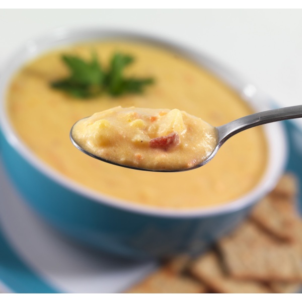 A spoon with a bowl of Augason Farms Corn Chowder Soup #10 Can - 20 Servings - (SHIPS IN 1-2 WEEKS) and crackers.