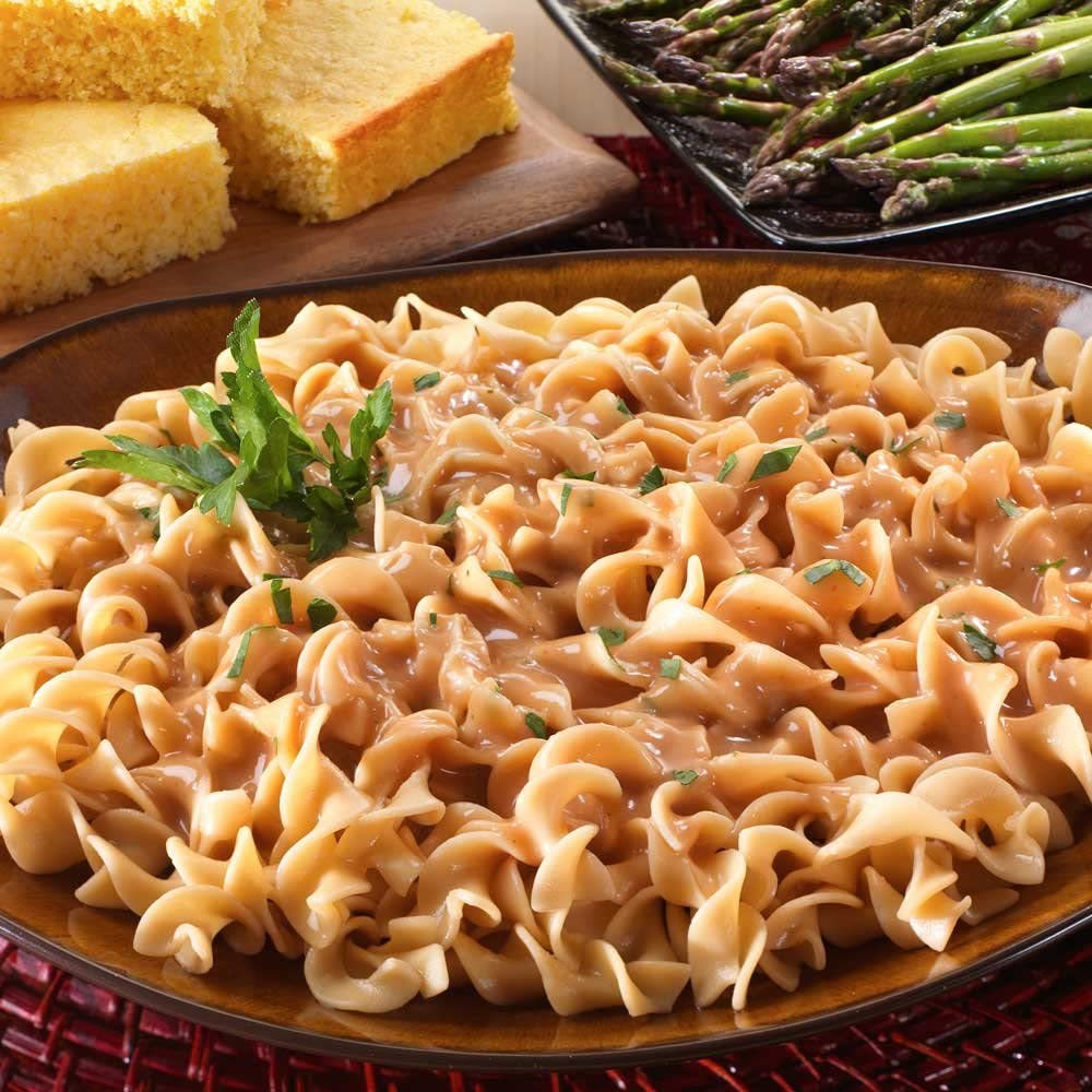 A Legacy Food Storage 6 Day Emergency Food Supply Kit - 32 Servings - 8 Entrees - (SHIPS IN 1-2 WEEKS) of pasta with gravy and asparagus.