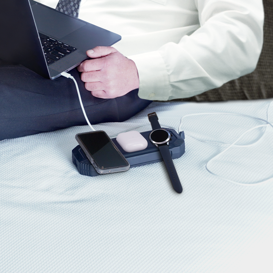 A man is sitting on a bed with a Lion Energy Lion Eclipse USB Power Bank With Wireless Charging - QI Charger.