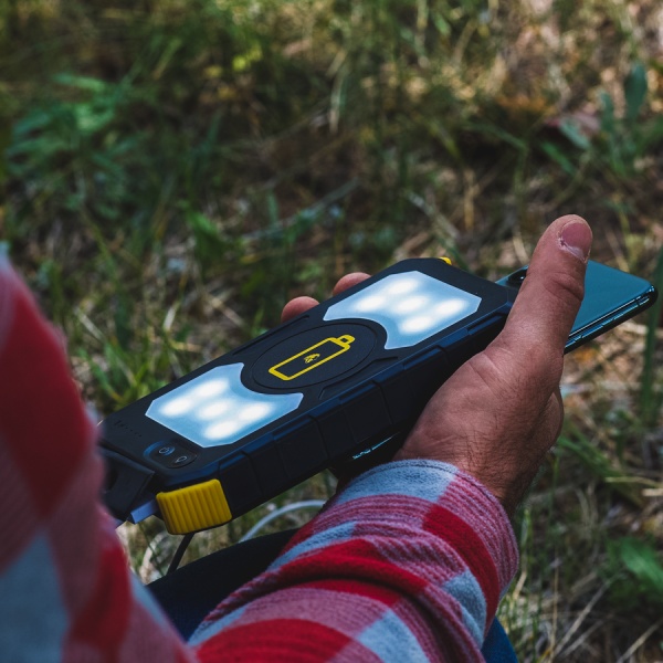 A person holding the Lion Energy Lion Prowler Power Bank With Wireless Charging - QI Charger in the grass.