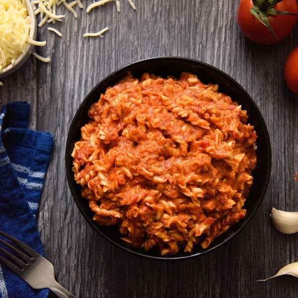 A bowl of Nutrient Survival Lasagna with meat and tomatoes on a wooden table.