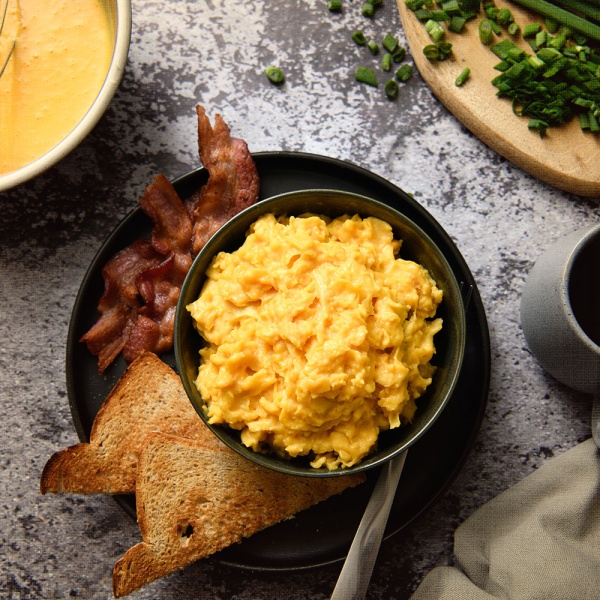A bowl of Nutrient Survival Powdered Vitamin Eggs - 70 Eggs in a #10 Can - 35 Servings - (SHIPS IN 2-4 WEEKS) with bacon and toast.