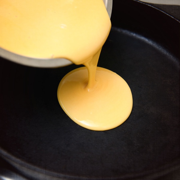 A frying pan with Nutrient Survival Powdered Vitamin Eggs - 70 Eggs in a #10 Can - 35 Servings - (SHIPS IN 2-4 WEEKS) melted cheese on it.