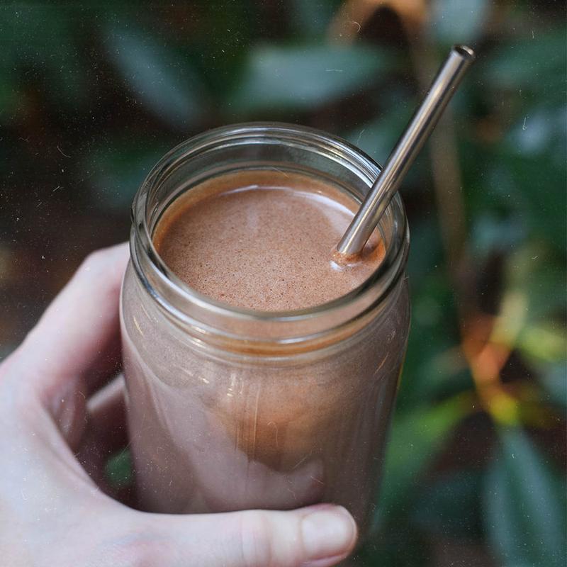 A person holding a jar of Nutrient Survival Non-GMO Vegetarian Gluten-Free Creamy Chocolate Shake SINGLES - (SHIPS IN 2-4 WEEKS).