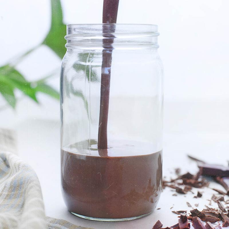 A jar of Nutrient Survival Non-GMO Vegetarian Gluten-Free Creamy Chocolate Shake SINGLES - (SHIPS IN 2-4 WEEKS) being poured into a jar.