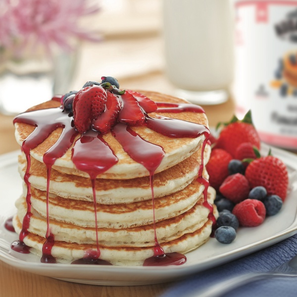 A stack of Augason Farms 5-Day 1-Person Survival Pail - 58 Servings - (SHIPS IN 1-2 WEEKS) with syrup and berries on a plate.