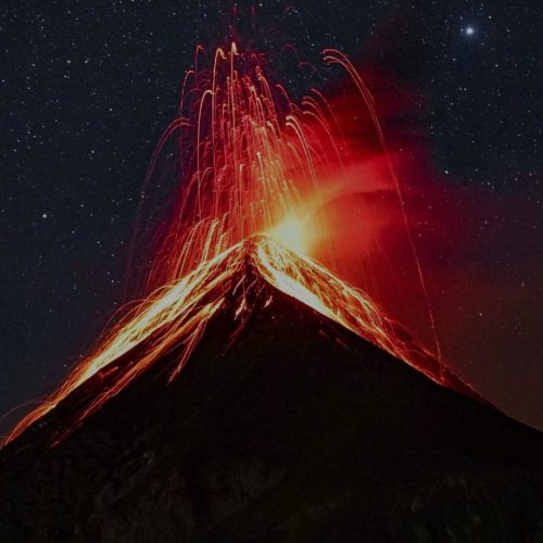 A volcano is lit up at night with a red glow.
