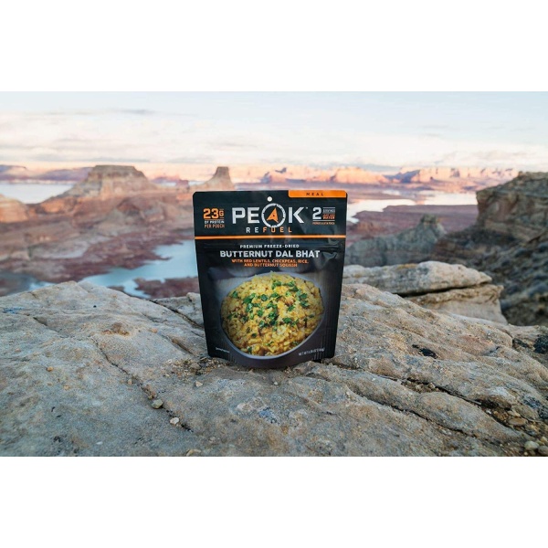 A bag of Peak Refuel Freeze-Dried Breakfast, Lunch, and Dinner Sampler Food Storage and Backpacking Food Kit - (SHIPS IN 1-2 WEEKS) sitting on top of a rocky cliff.