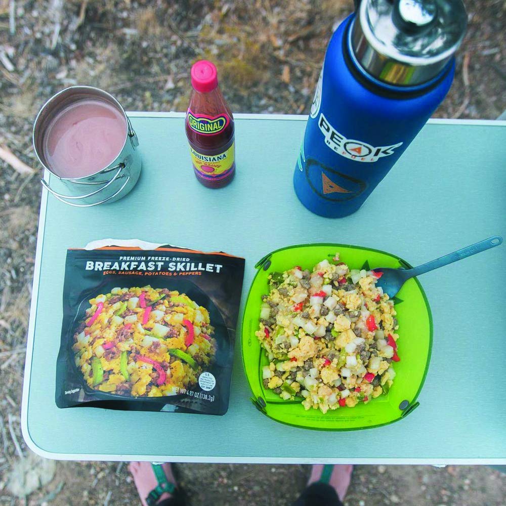 A table with a Peak Refuel Freeze-Dried Breakfast Sampler Food Storage and Backpacking Kit - (SHIPS IN 1-2 WEEKS) and a bottle of water.