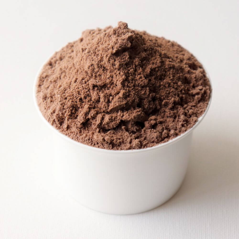 Chocolate powder in a white cup on a white surface.