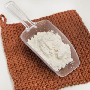 A scoop of flour on a crocheted cloth.