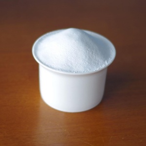 White powder in a cup on a wooden table.