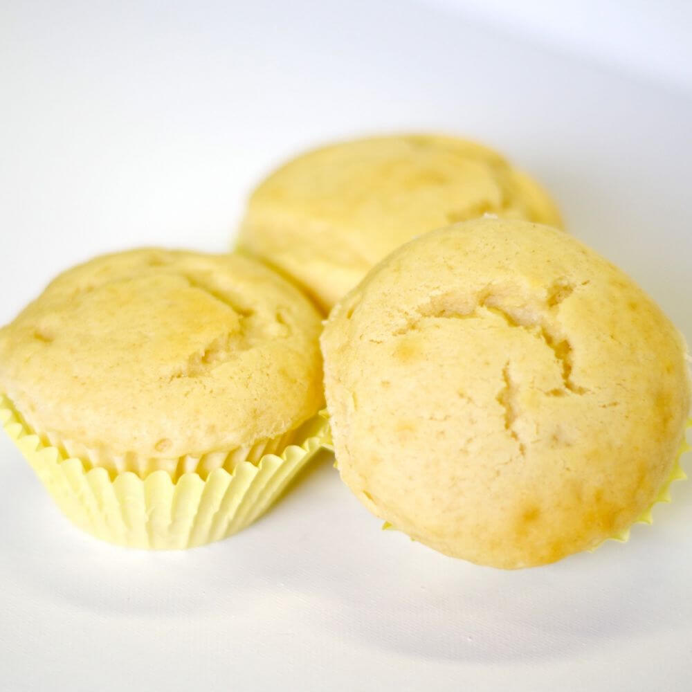 Three muffins are sitting on a white surface.