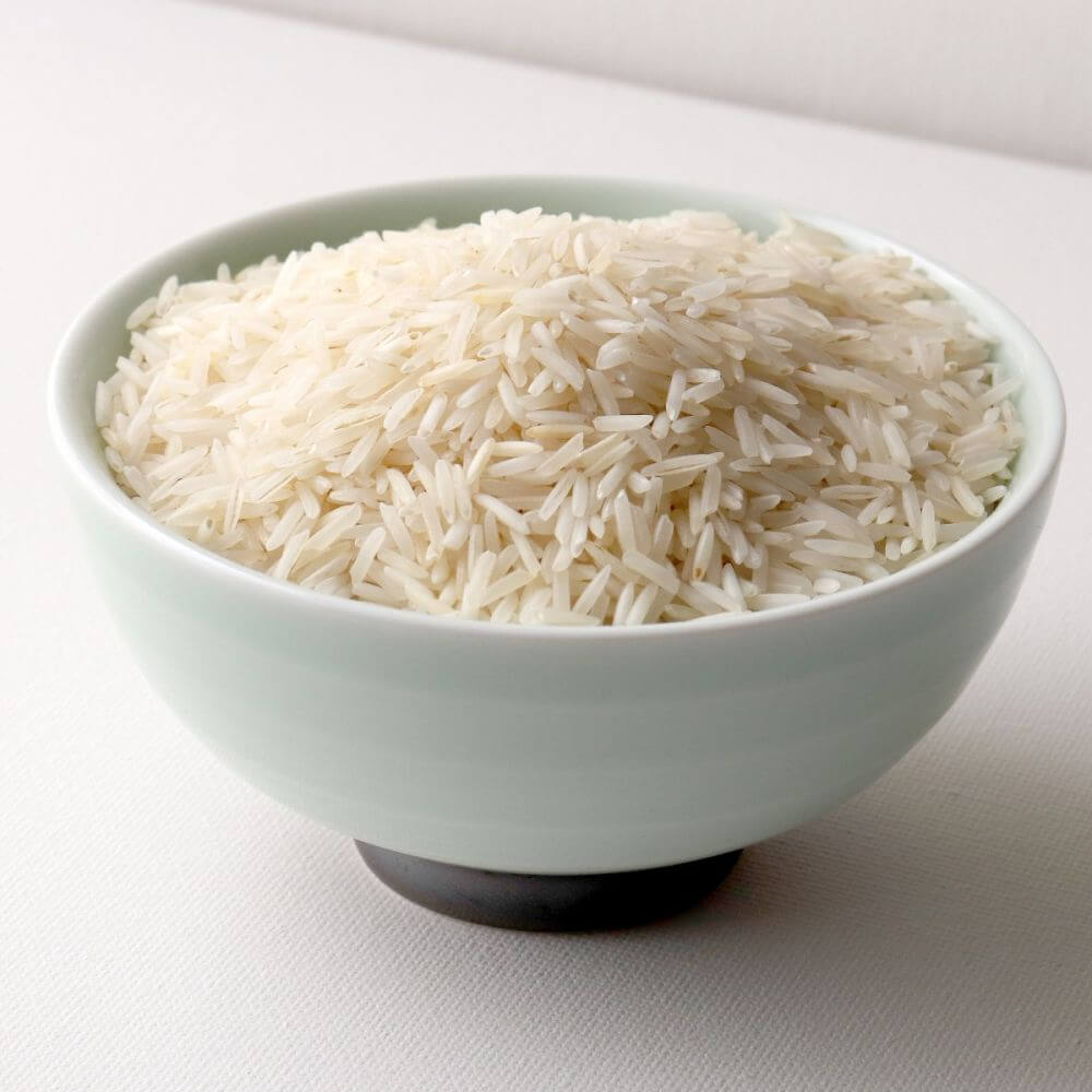 White rice in a bowl on a white surface.