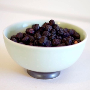Blueberries in a bowl on a white table.