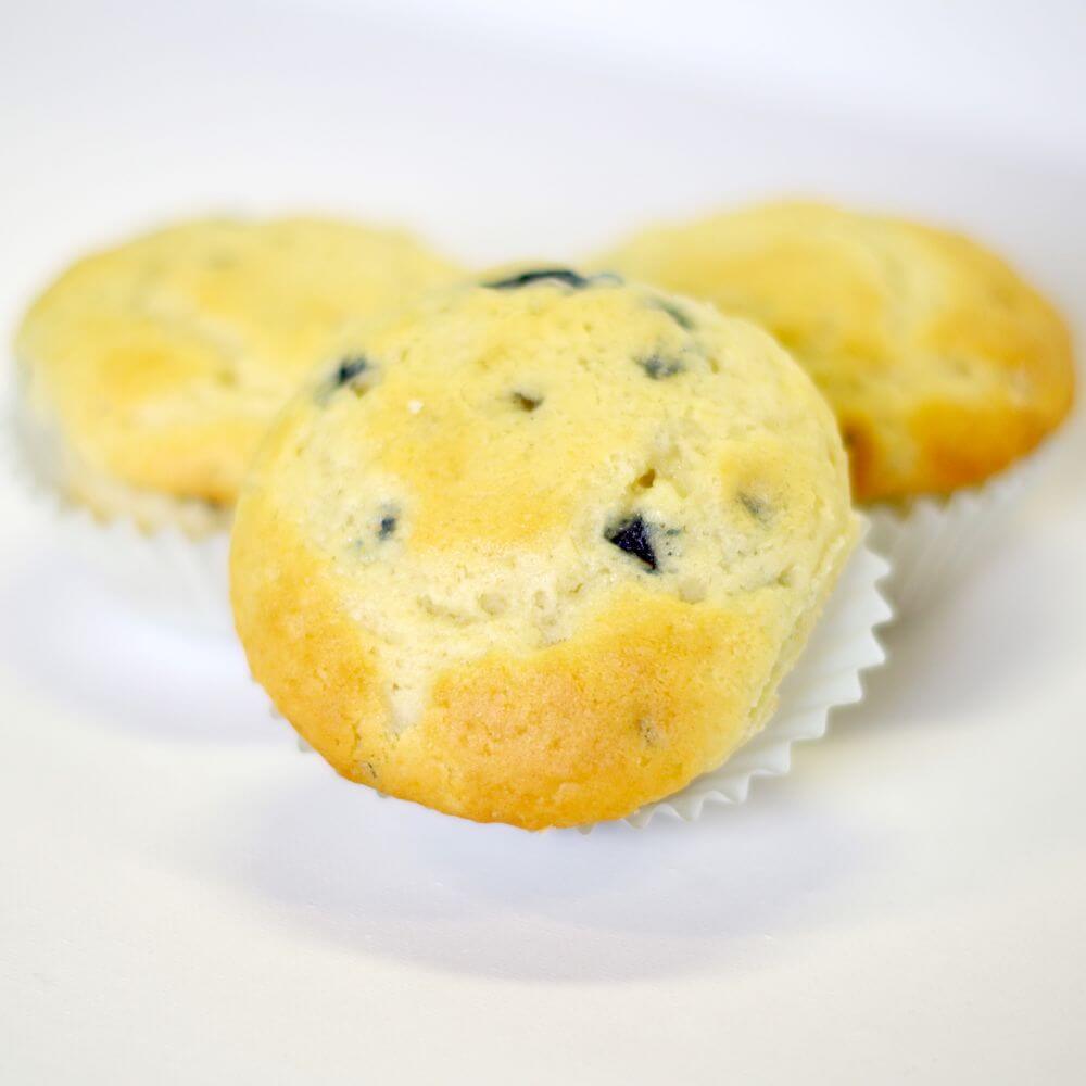 Three blueberry muffins on a white surface.