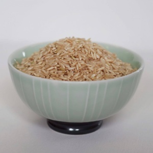 Brown rice in a bowl on a white surface.