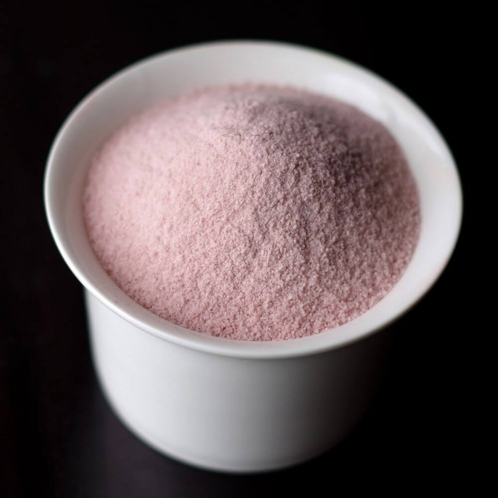 Pink sugar in a bowl on a table.