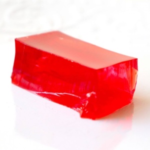 A piece of red gummy candy sitting on top of a white surface.