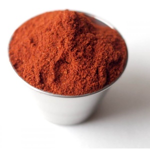 Red chili powder in a cup on a white background.