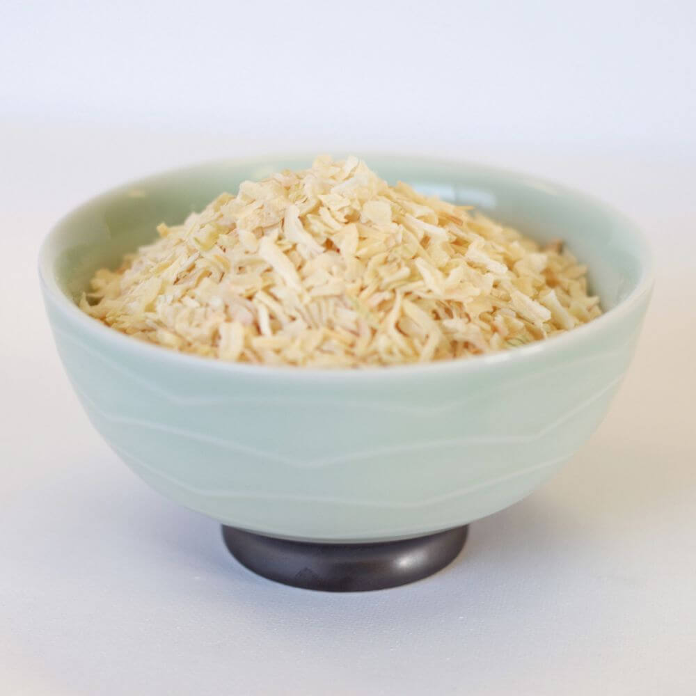 A bowl of shredded carrots on a white surface.