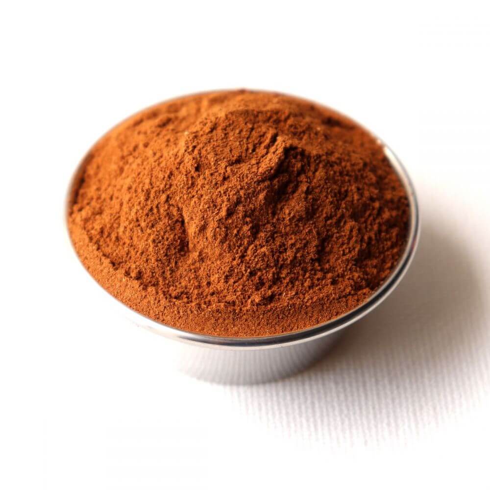 Cocoa powder in a small bowl on a white background.