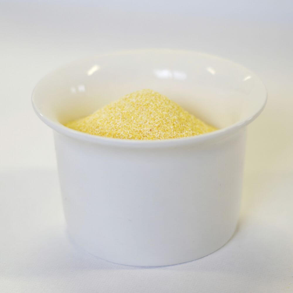 A bowl of yellow sugar on a white surface.