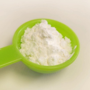 White powder in a green spoon on a white background.