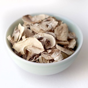 Dried mushrooms in a bowl on a white surface.