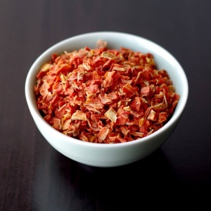 A bowl of chopped red peppers on a table.