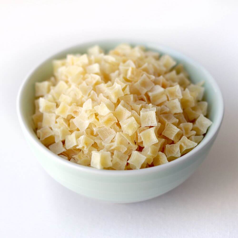 A bowl of shredded cheese on a white surface.