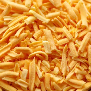 Shredded cheddar cheese in a bowl.