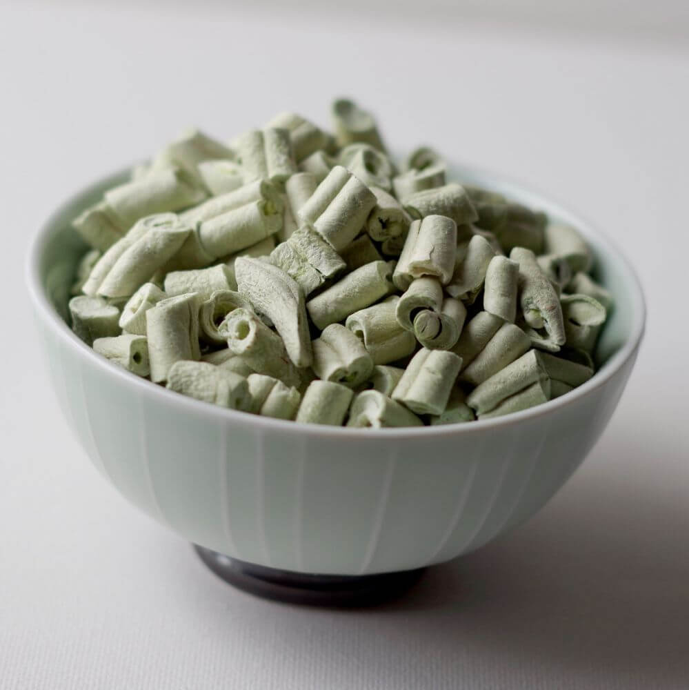 A bowl full of green leaves in a white bowl.