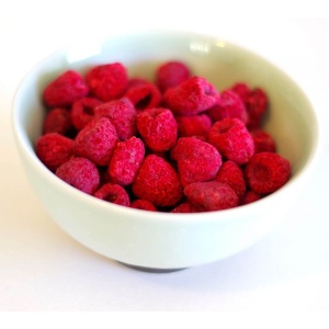 Raspberries in a bowl on a white surface.