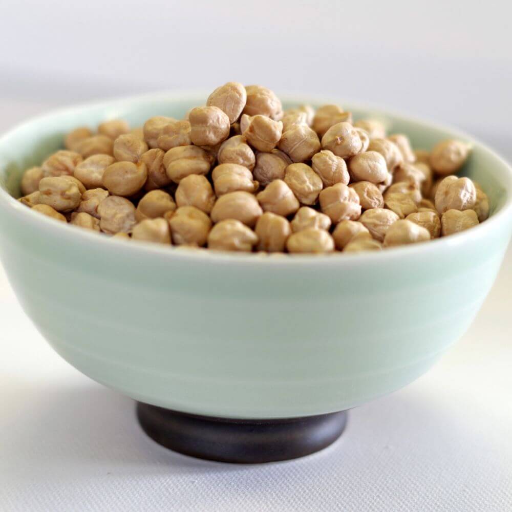 Chickpeas in a bowl on a white surface.