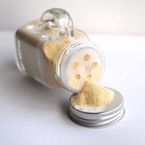A glass jar with a yellow powder in it.