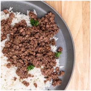 A plate of rice and ground beef on a wooden table, suitable for emergency food storage.