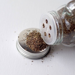 A glass jar with a small amount of seasoning in it.