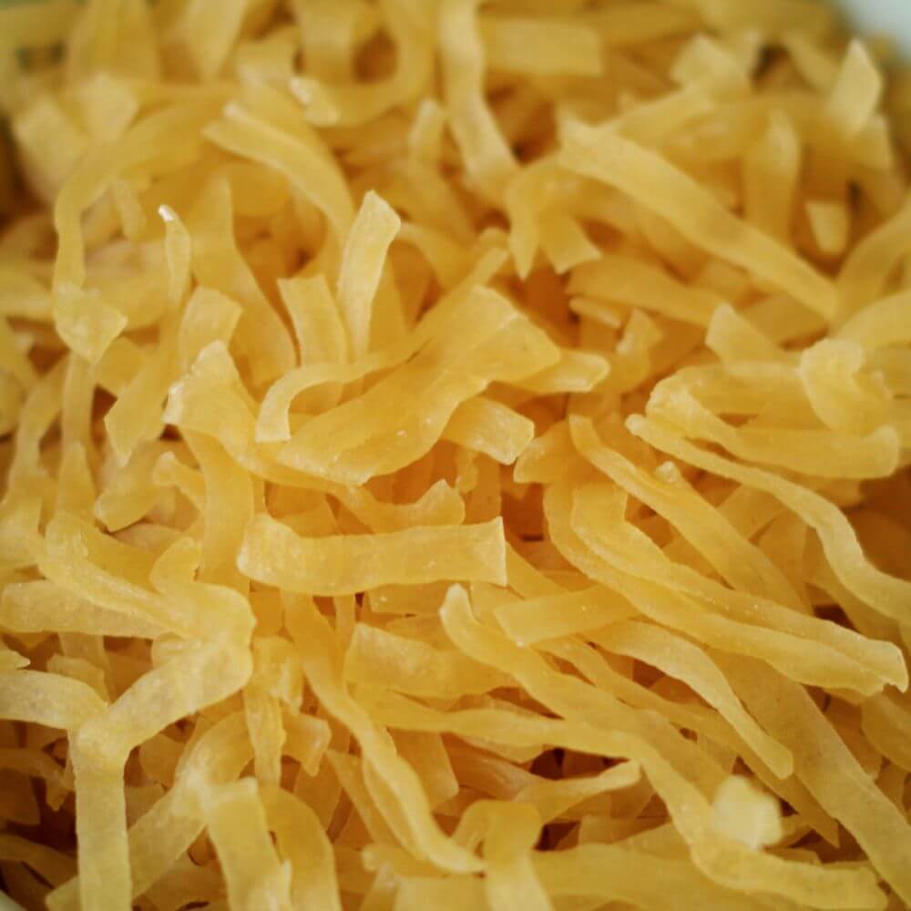 A close up of yellow noodles in a bowl.
