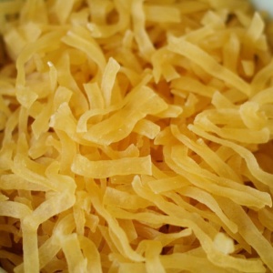 A bowl of yellow noodles in a white bowl.