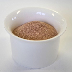 Cocoa powder in a white bowl on a white surface.